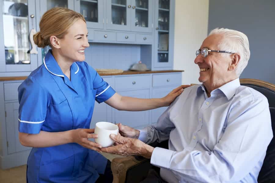 nurse giving elderly man a cup of tea