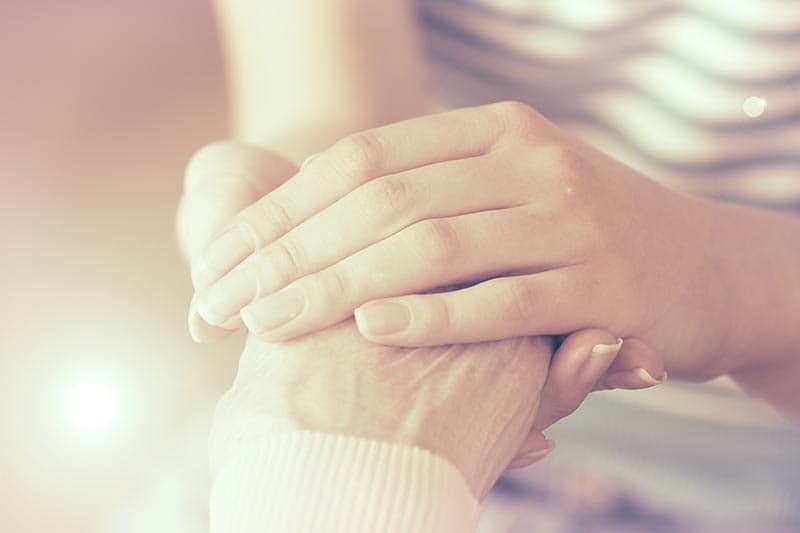 young person holding hands with old person